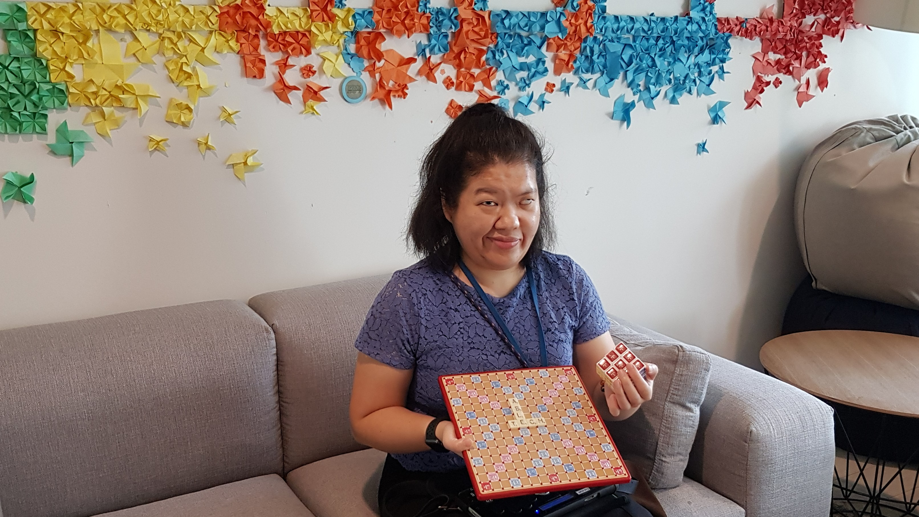 Siew Ling posing with the adapted Scrabble board and puzzle cube. 