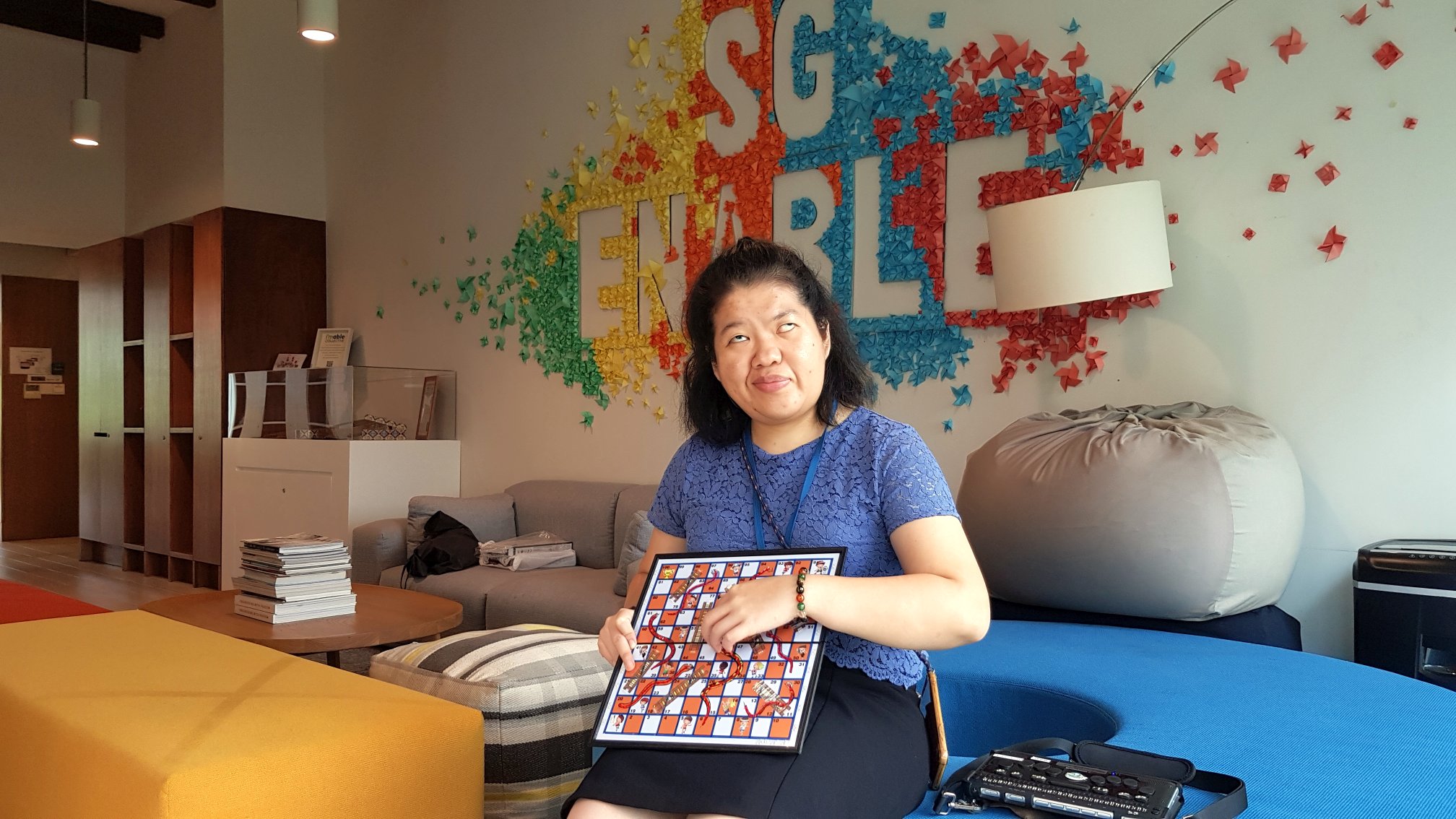 Siew Ling holding and touching the surface of the adapted Snakes and Ladders game.