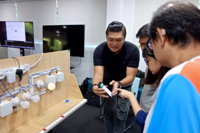 A workshop trainer showing participants how to use a Smart Home device