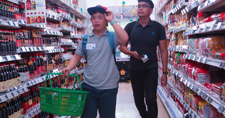 An independent travel project participant shops at the FairPrice supermarket at the Enabling Village