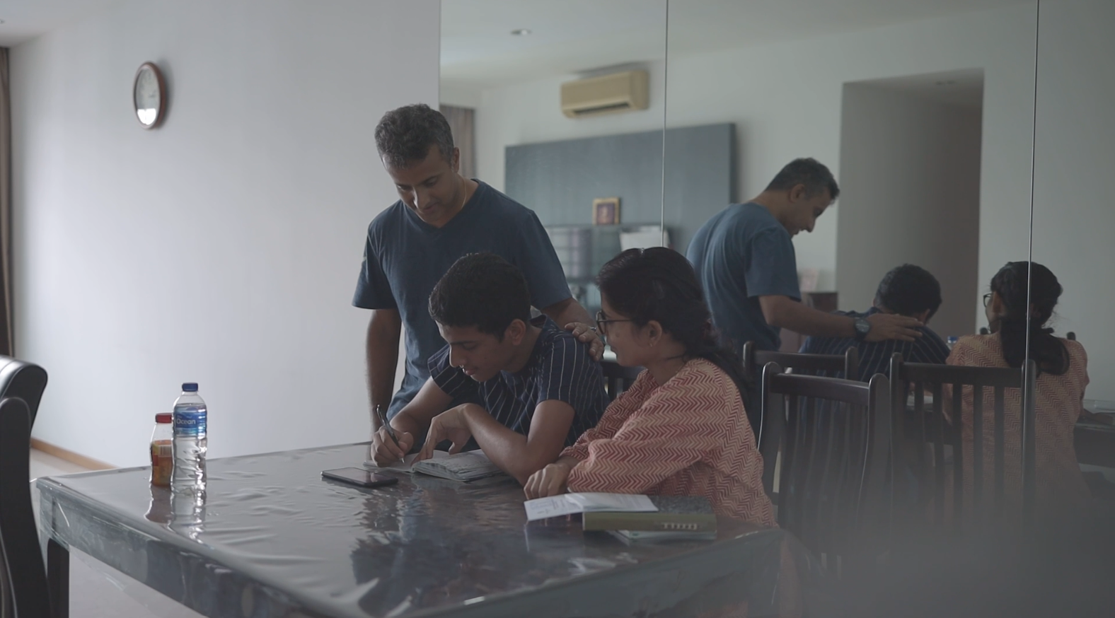 Parents guiding their son with autism on his school. seated at a dining table